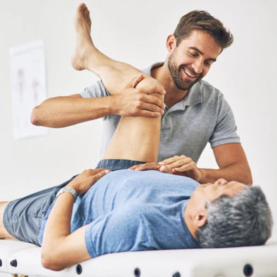 A physical therapist stretching a patient's hip