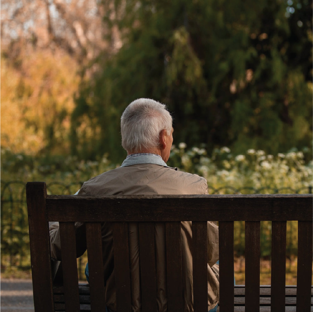 An elderly man sitting alone on a bench