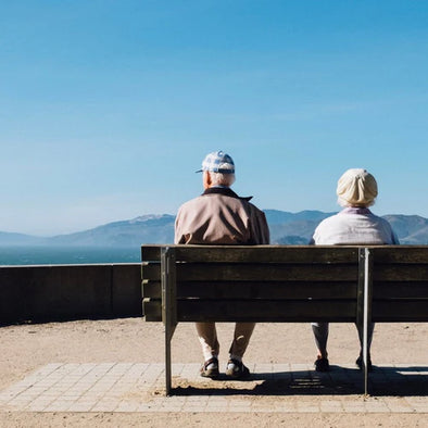 An elderly man and woman sitting on a bench