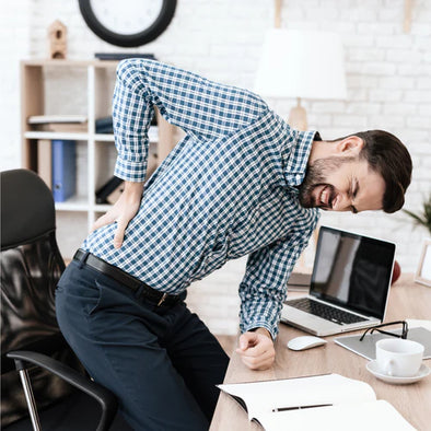 A man standing up holding his back in pain