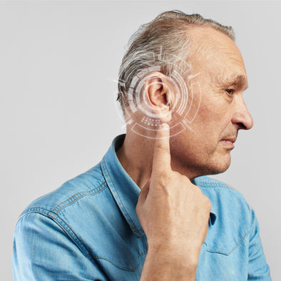 An elderly man pointing to his ear