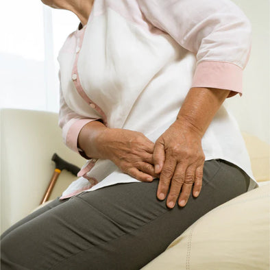 An elderly woman holding her hip in pain
