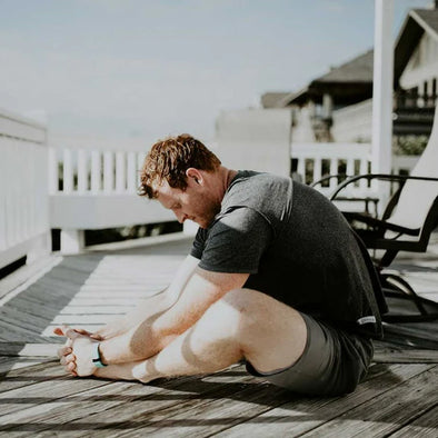 A man sitting outside doing a butterfly stretch