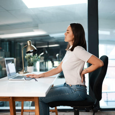 A woman at a desk with back pain