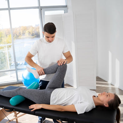 A physical therapist stretching a patient's hip while they're on a bed