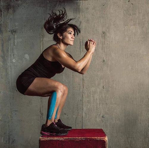 A woman jumping on a box with kinesiology tape on her leg