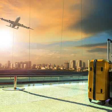 Luggage in an airport in front of a window with a plane taking off