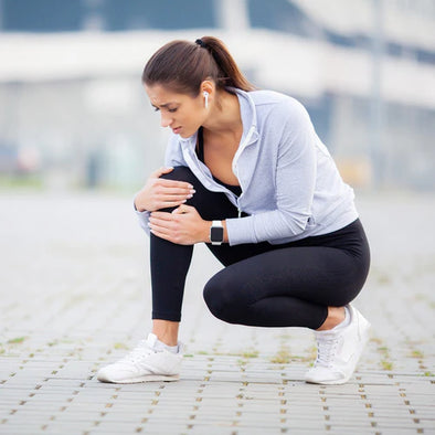 A woman bent over holding her knee in pain