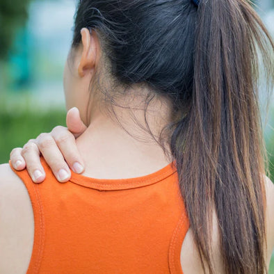 A woman holding her upper back in pain