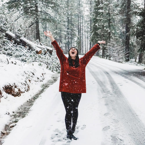 A woman in snow with her hands up