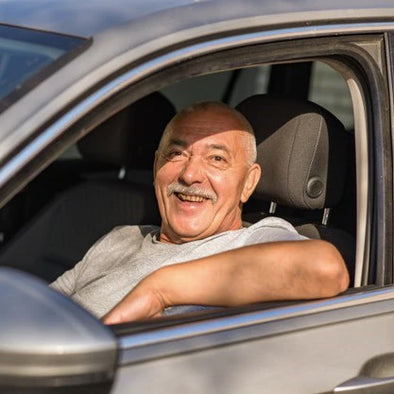 An elderly man smiling while sitting in his car