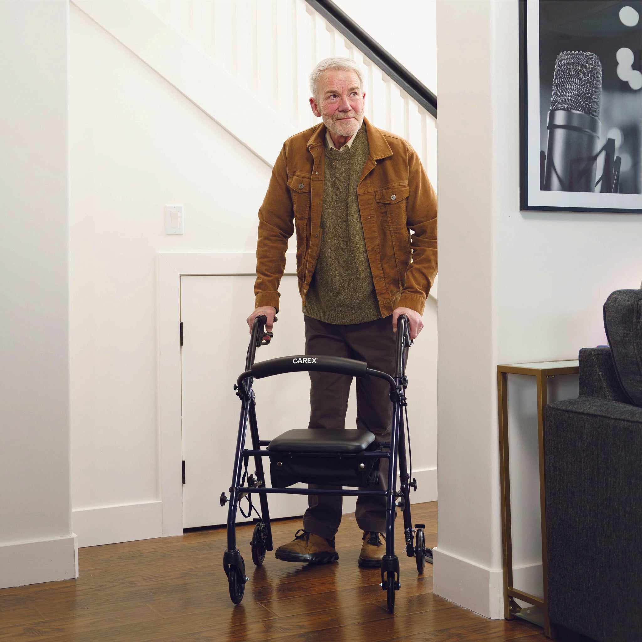 An elderly man walking inside with the Carex Steel Rolling Walker