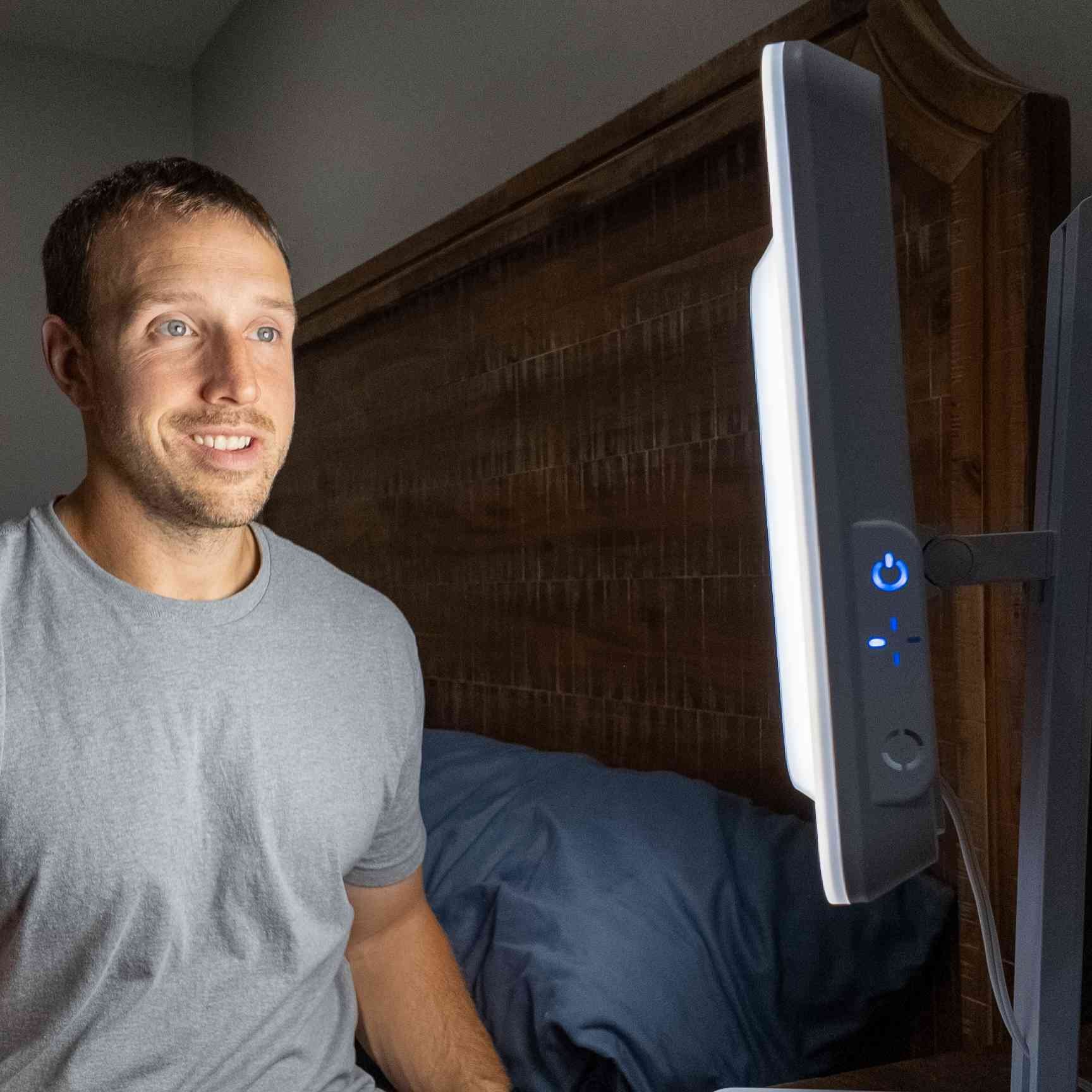 A man sitting in front of the Day-Light Elite Light Therapy Lamp