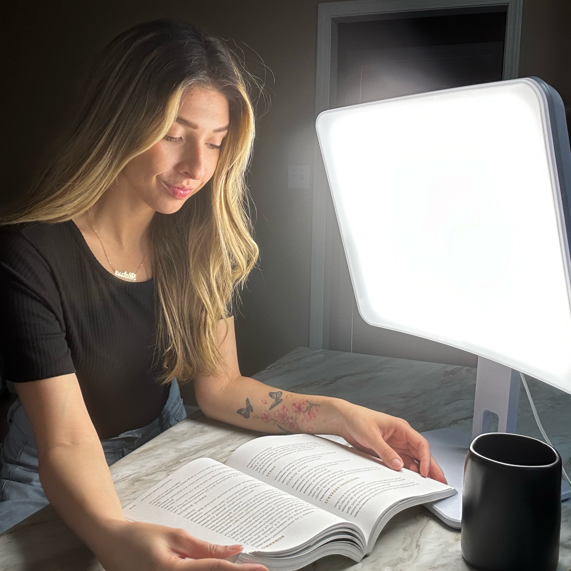 A woman reading in front of the  Day-Light Elite Light Therapy Lamp