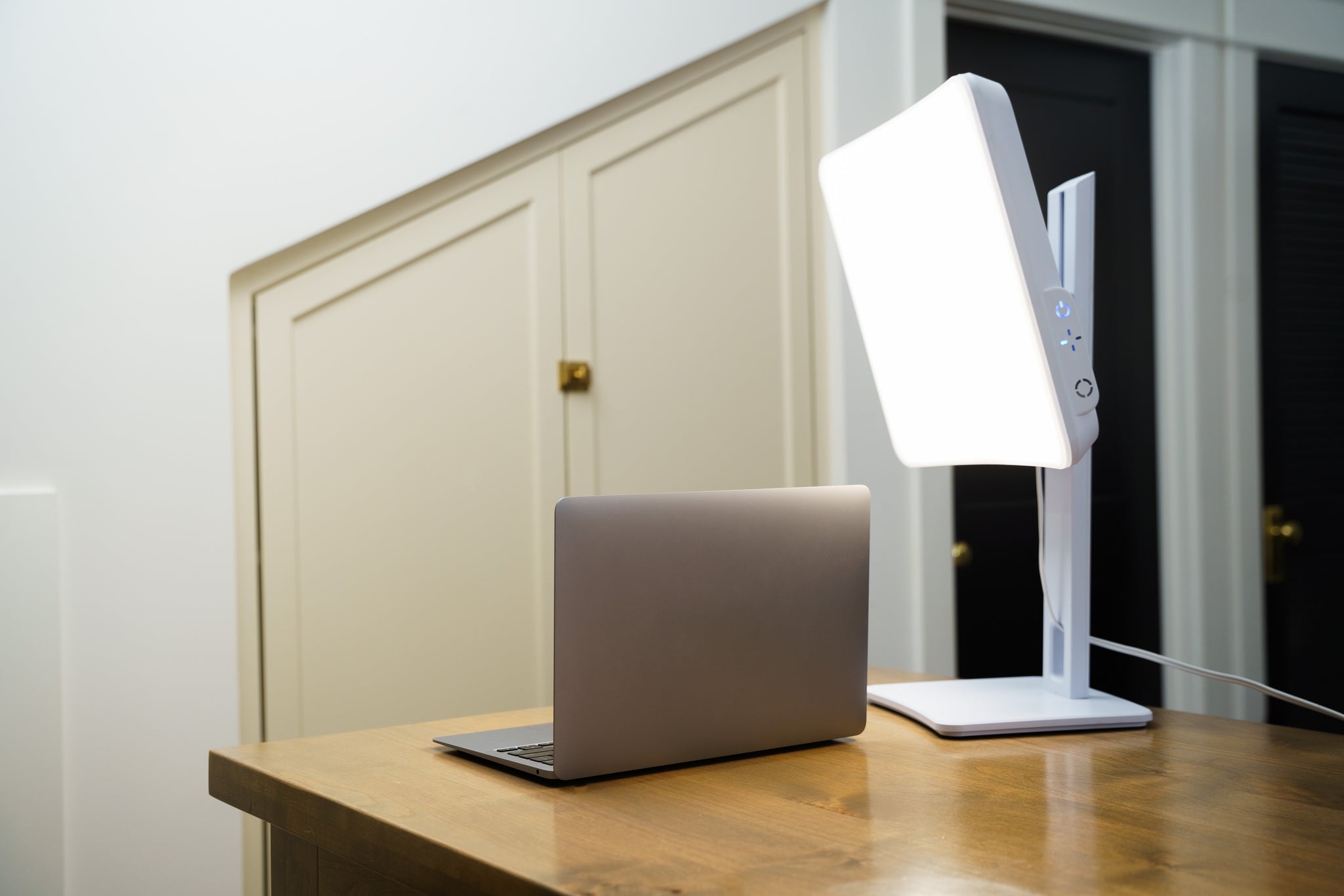 A white light therapy lamp on a desk next to a computer