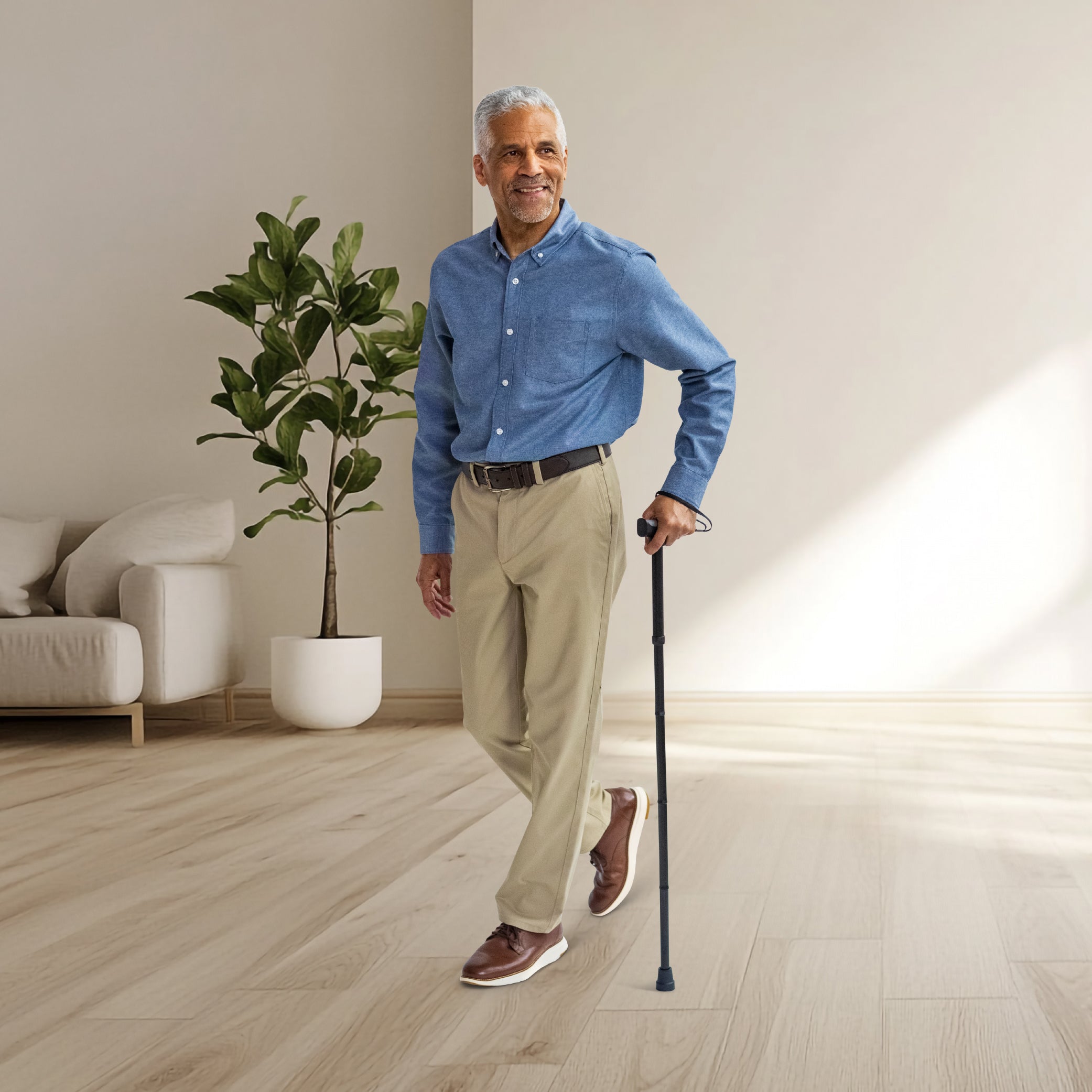 Man standing in a modern living room holding a cane.