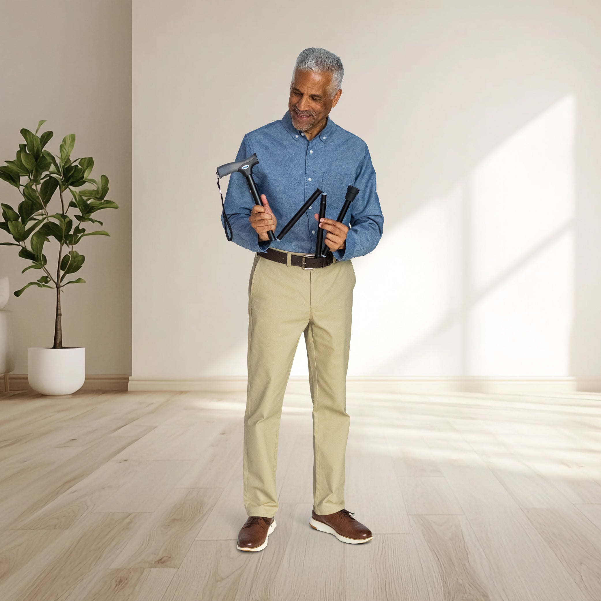 Man holding a belt with multiple loops in a room with a plant and light-colored floor.