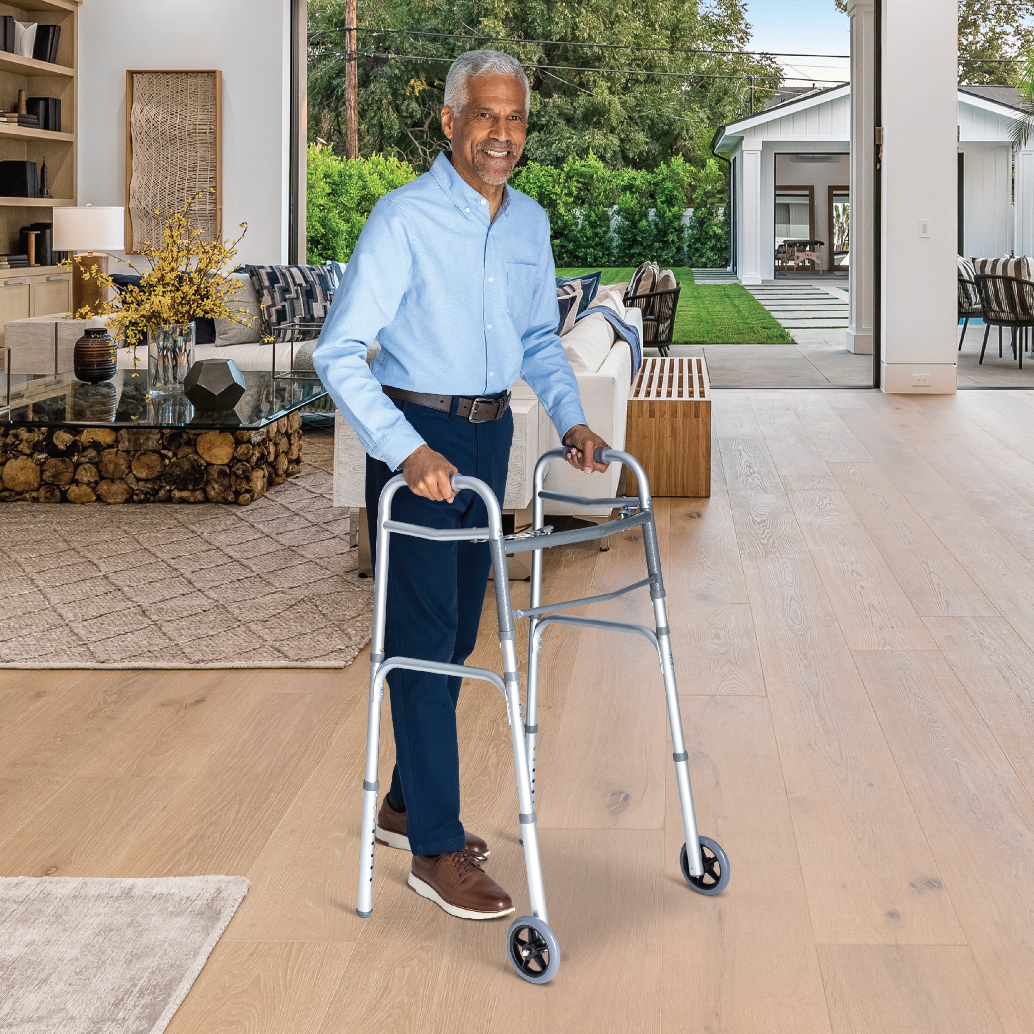 Man using a walker in a living room with a view of a garden.